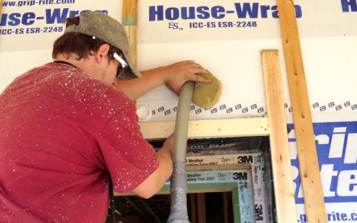 Cellulose being blown into wall cavity