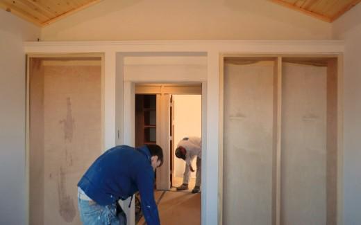 Anthony sanding built-in bookshelves in library